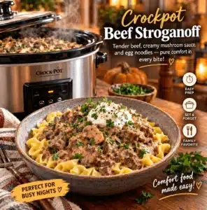 Creamy slow cooker beef stroganoff served over egg noodles in a white bowl, garnished with fresh parsley and sour cream.